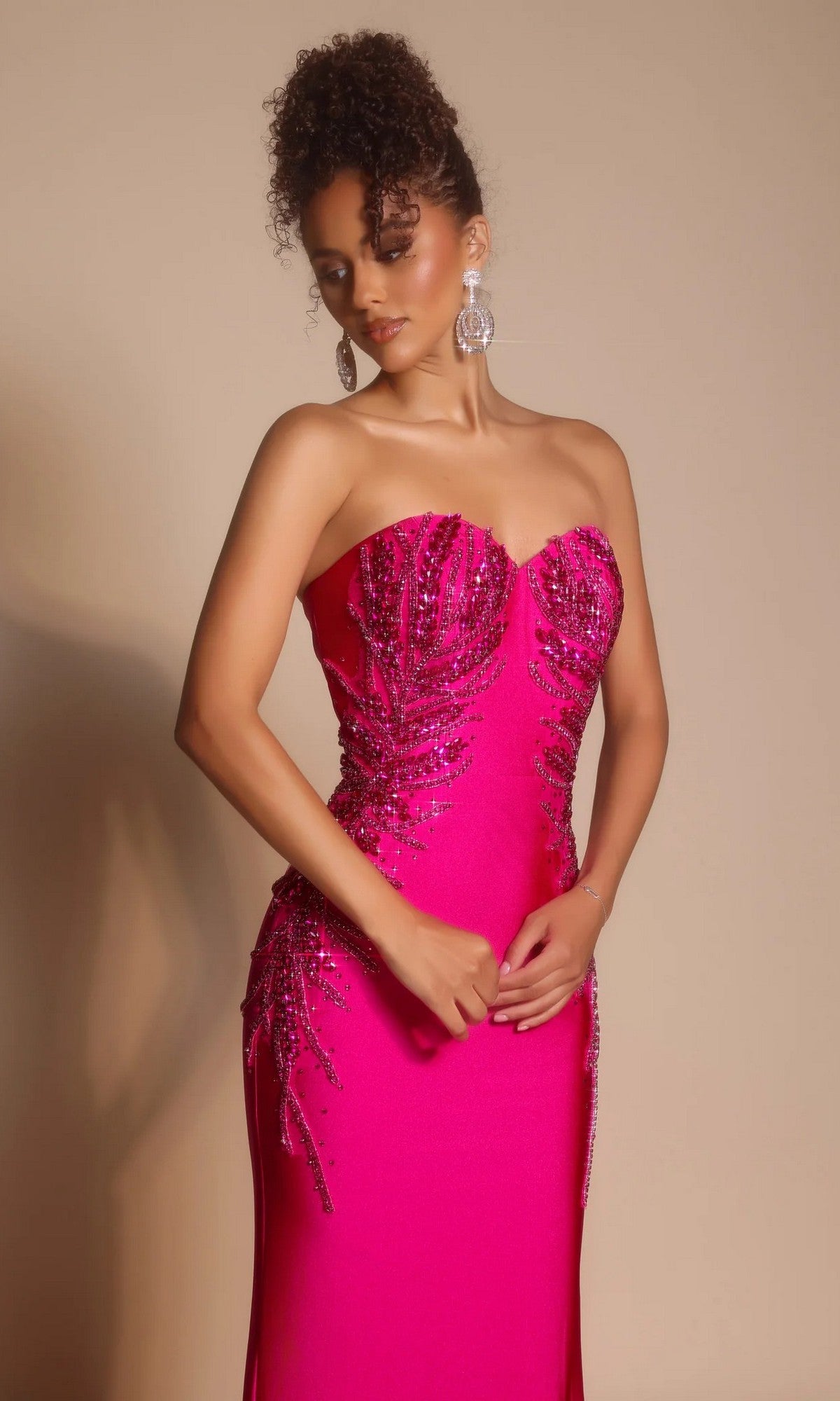 Woman wearing the Portia and Scarlett PS26331E long formal dress, featuring a strapless sweetheart neckline in bright pink with sequin embellishments, large dangling earrings, and curly updo against a neutral background.
